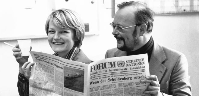 A man and a woman are reading a German version of Development Business issue