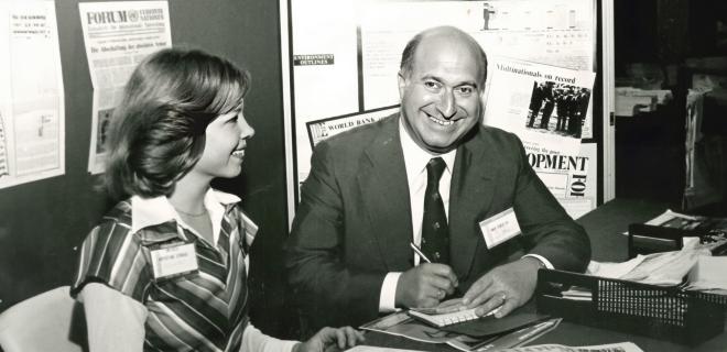 Historical photo of a man is writing and sitting beside a woman